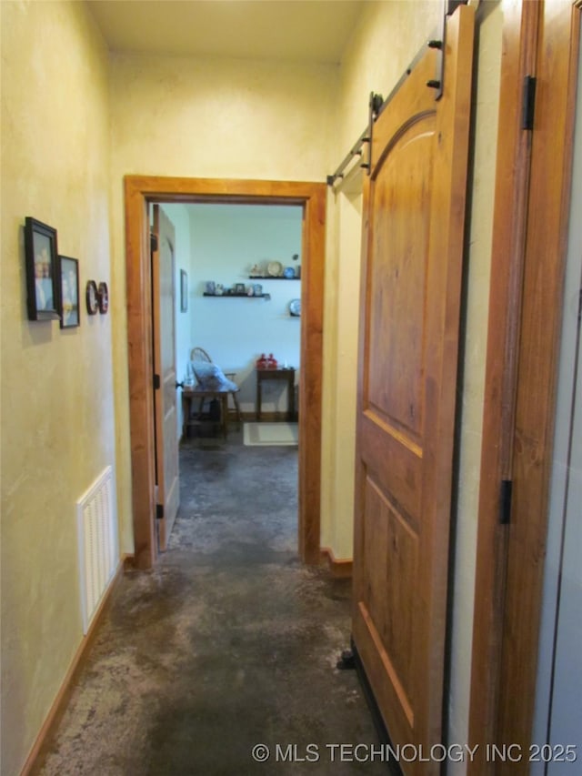 hallway with visible vents, concrete floors, and a barn door