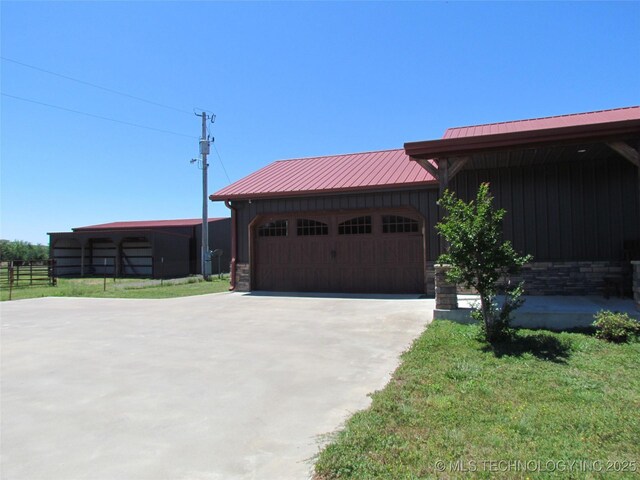 view of front of house with fence, driveway, a garage, board and batten siding, and metal roof