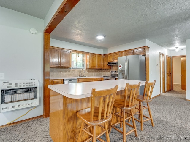 kitchen with heating unit, a sink, light countertops, appliances with stainless steel finishes, and light carpet