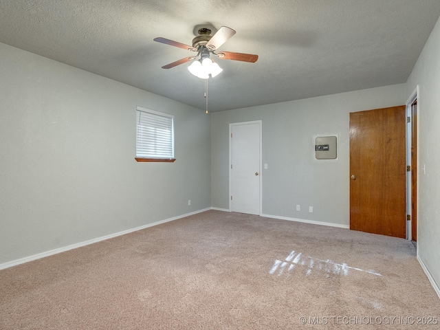 spare room with a textured ceiling, baseboards, carpet floors, and ceiling fan