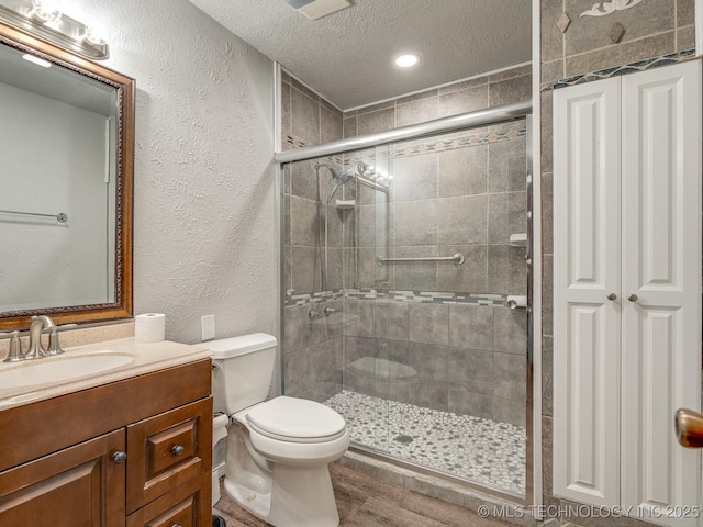 full bathroom with a textured wall, a stall shower, and a textured ceiling