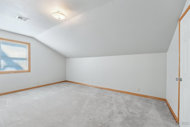 additional living space featuring visible vents, baseboards, light colored carpet, and vaulted ceiling