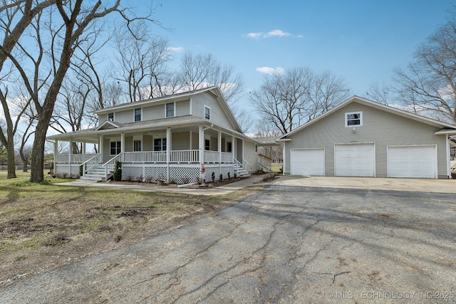 country-style home featuring covered porch, an outdoor structure, and driveway