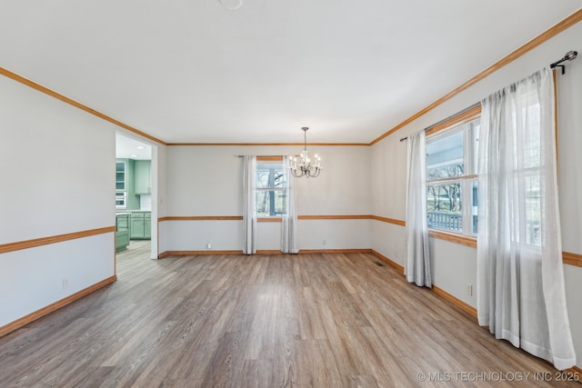 unfurnished room featuring a chandelier, crown molding, baseboards, and wood finished floors