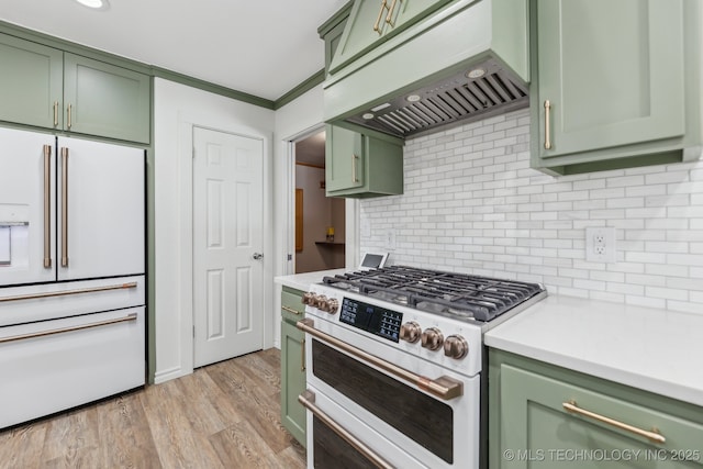 kitchen with green cabinets, under cabinet range hood, light countertops, light wood-style flooring, and white appliances