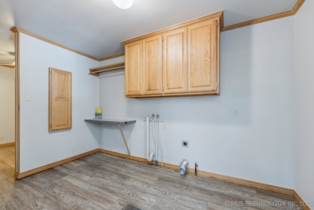 laundry room featuring baseboards, ornamental molding, wood finished floors, cabinet space, and hookup for an electric dryer