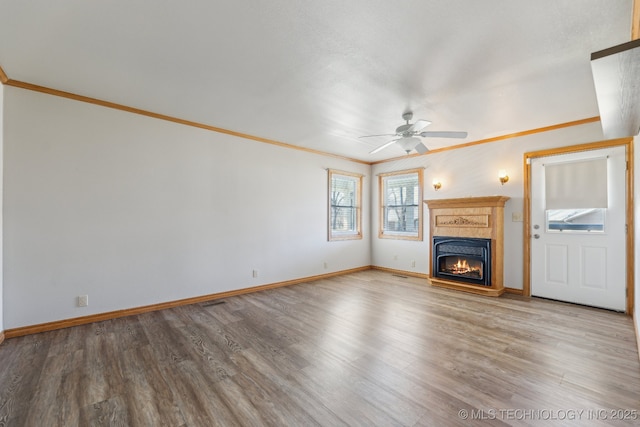 unfurnished living room featuring a ceiling fan, a glass covered fireplace, wood finished floors, and ornamental molding