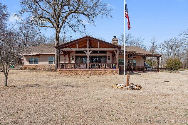 view of front of property featuring stucco siding, driveway, a chimney, and a pergola