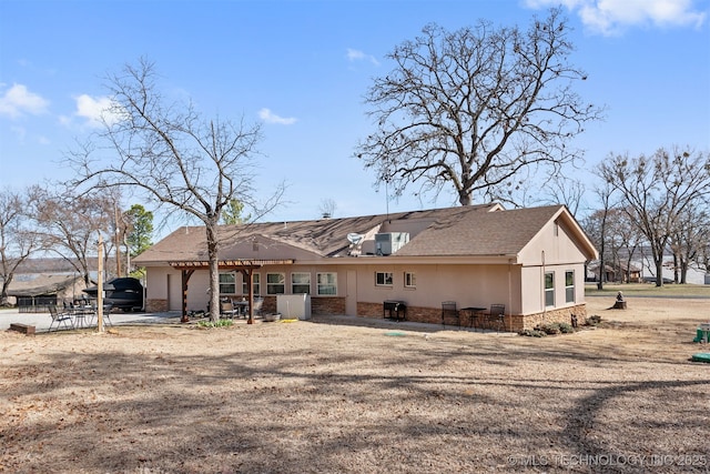 rear view of house with a patio area, stone siding, stucco siding, and a pergola