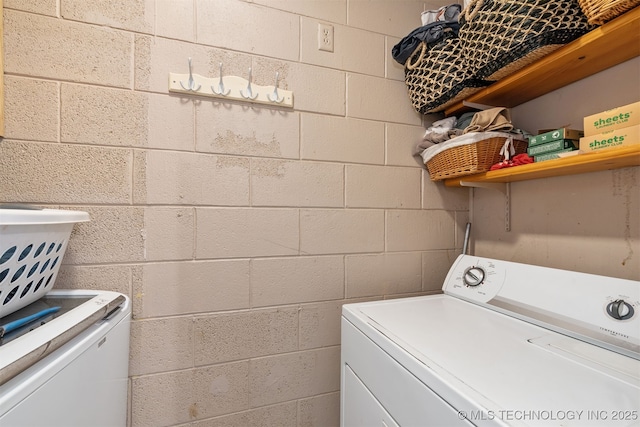 laundry area featuring laundry area, washer and dryer, and concrete block wall