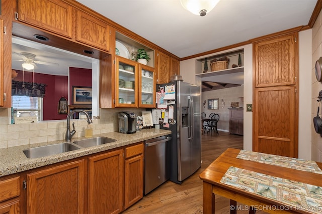 kitchen with a sink, glass insert cabinets, brown cabinetry, and stainless steel appliances