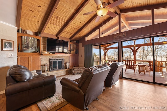 living area with a stone fireplace, wooden ceiling, vaulted ceiling with beams, and wood finished floors