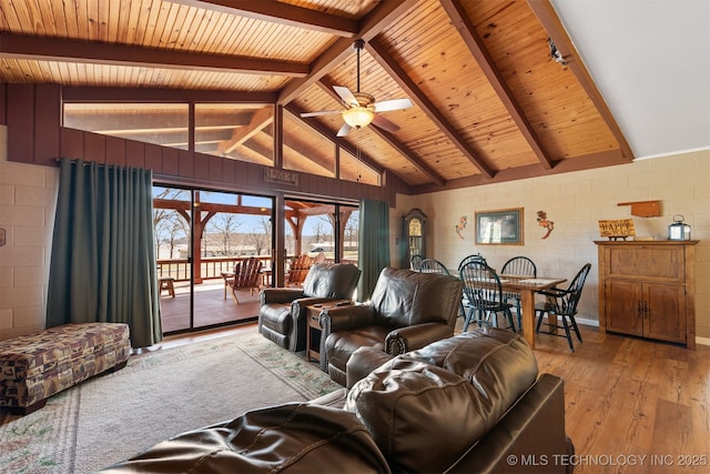 living area with a ceiling fan, wooden ceiling, concrete block wall, light wood finished floors, and vaulted ceiling with beams