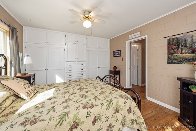 bedroom with crown molding, wood finished floors, a closet, and ceiling fan