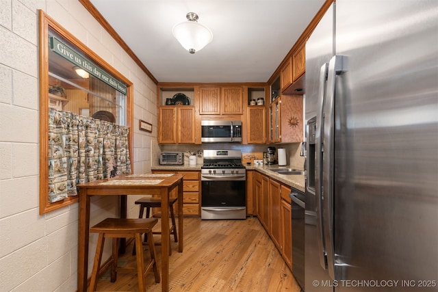 kitchen with light wood-type flooring, open shelves, ornamental molding, appliances with stainless steel finishes, and brown cabinets