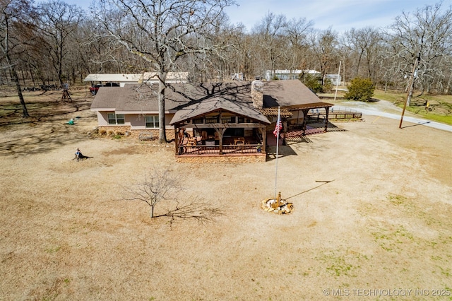 rear view of property featuring a chimney and driveway