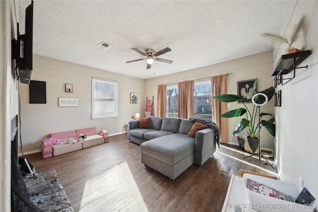 living room with visible vents, ceiling fan, a fireplace, wood finished floors, and a textured ceiling