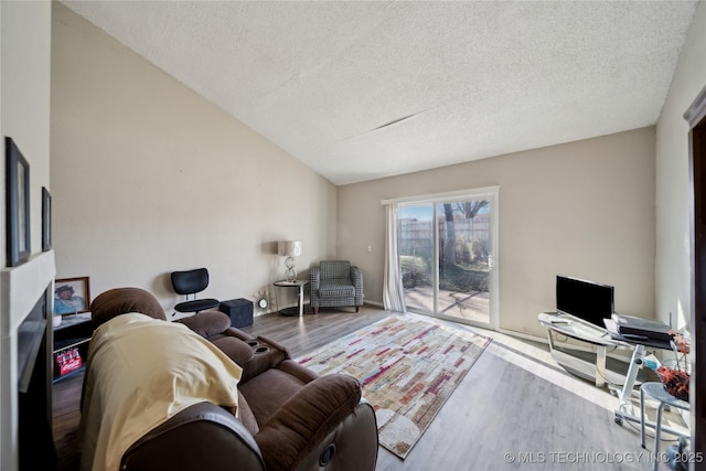 living room with lofted ceiling, a textured ceiling, and wood finished floors