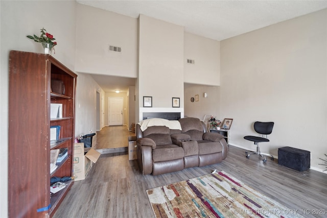 living area featuring visible vents, wood finished floors, and a towering ceiling