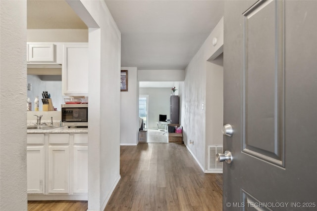 foyer entrance featuring visible vents, baseboards, and wood finished floors