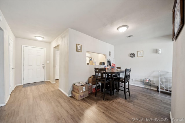 dining space with visible vents, baseboards, and wood finished floors