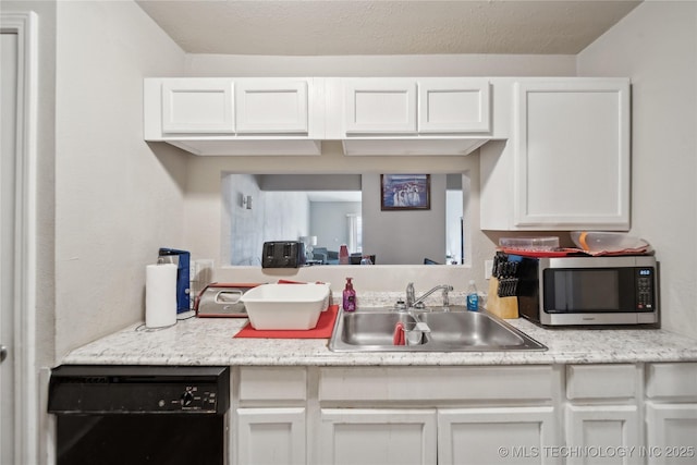 kitchen with a sink, stainless steel microwave, black dishwasher, and light countertops