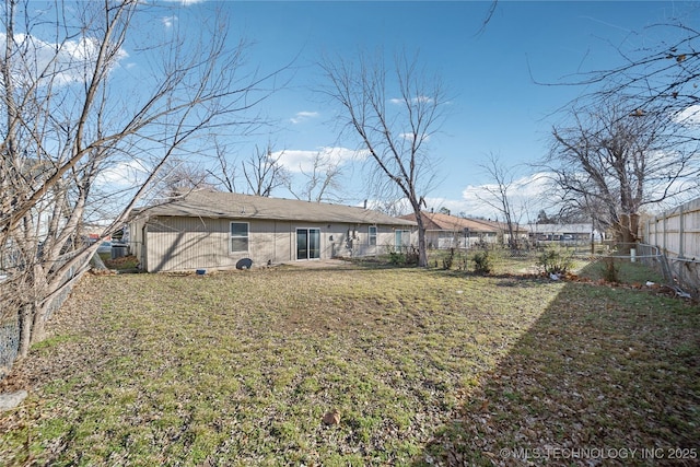 rear view of house with a lawn and a fenced backyard