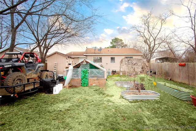 back of property featuring a yard, a vegetable garden, an outdoor structure, and fence