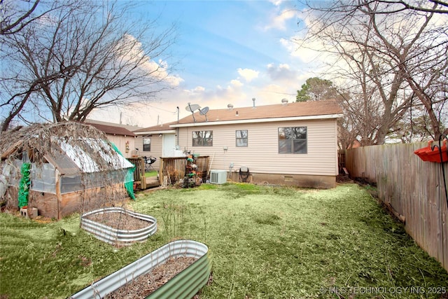 rear view of property with central AC unit, a yard, a fenced backyard, an outdoor structure, and a greenhouse