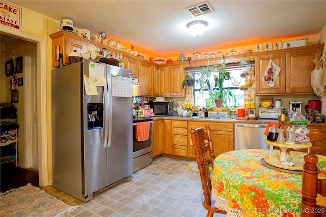 kitchen with visible vents, light floors, light countertops, stainless steel appliances, and a sink