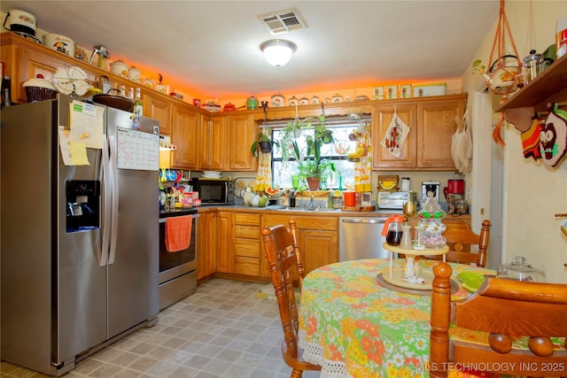 kitchen featuring visible vents, brown cabinets, a sink, stainless steel appliances, and light floors