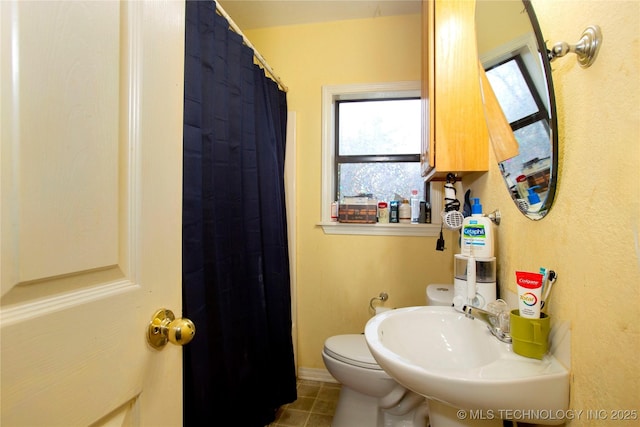 bathroom featuring a sink, curtained shower, toilet, and tile patterned flooring