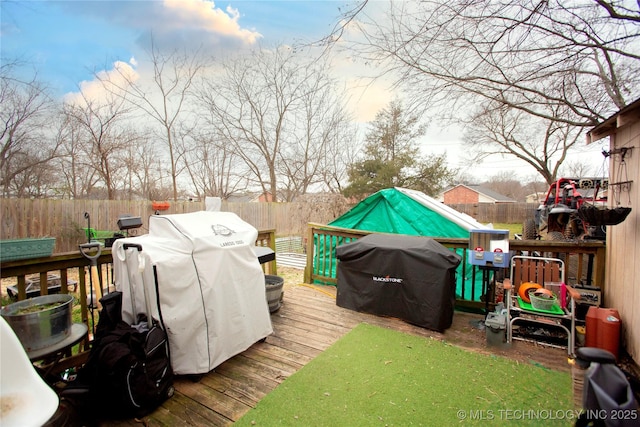 wooden terrace with a fenced backyard and a grill