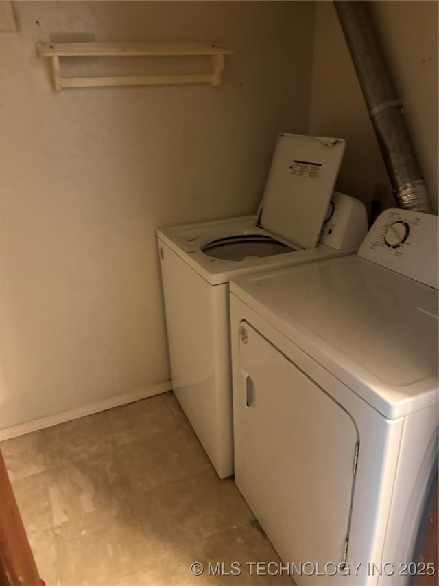 washroom featuring laundry area, baseboards, and separate washer and dryer