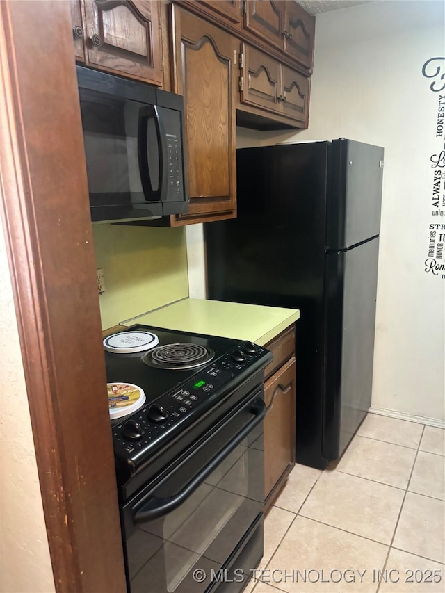 kitchen featuring black appliances, light tile patterned flooring, and light countertops