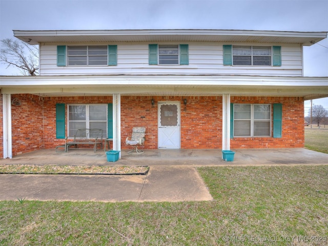 traditional-style house with a front lawn, brick siding, and covered porch