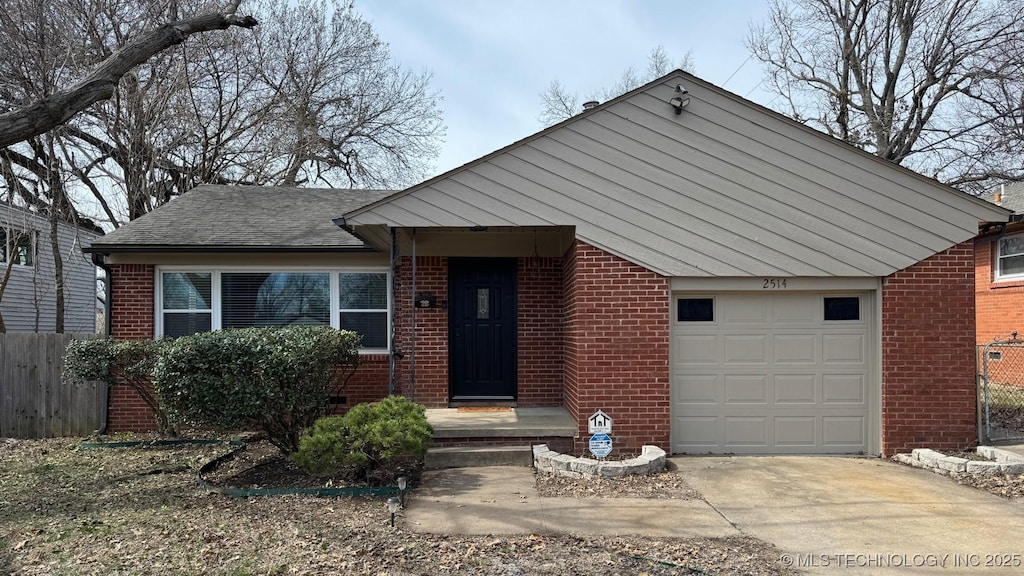 view of front of house featuring driveway, fence, roof with shingles, an attached garage, and brick siding