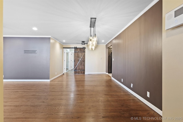 interior space with ornamental molding, baseboards, a barn door, and wood finished floors