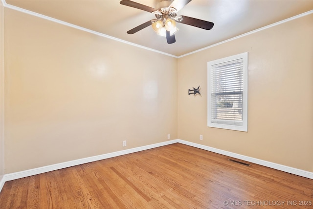 spare room with crown molding, wood finished floors, baseboards, and visible vents