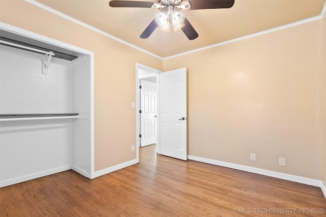 unfurnished bedroom with a ceiling fan, wood finished floors, baseboards, a closet, and crown molding