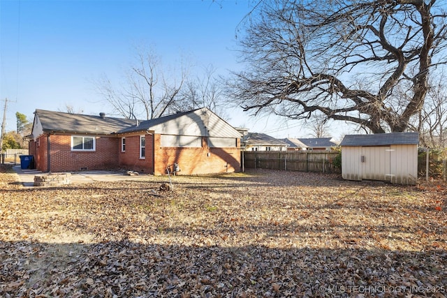 back of property featuring an outbuilding, a patio, fence, crawl space, and brick siding