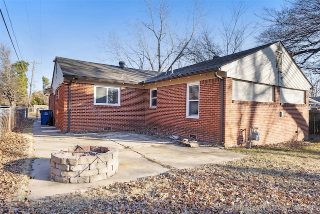 back of house featuring a patio, an outdoor fire pit, fence, crawl space, and brick siding