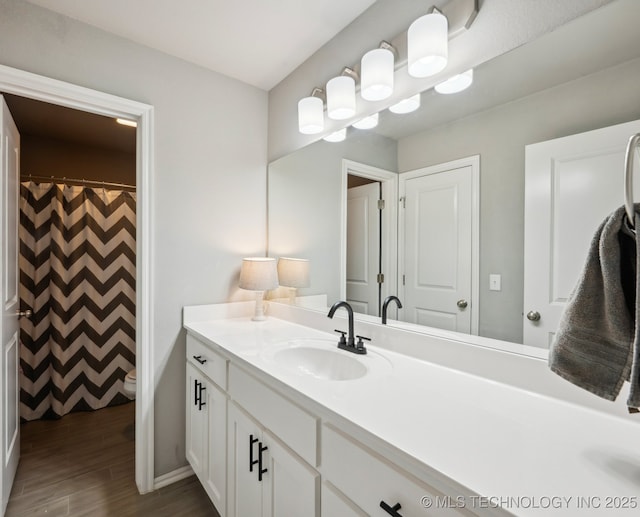 full bath with toilet, wood finished floors, and vanity