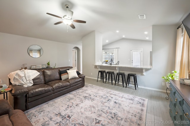 living room with ceiling fan, baseboards, lofted ceiling, wood finished floors, and arched walkways