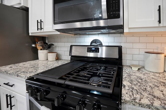 5117 S Nassau Ave, Sand Springs, OK 74063 - kitchen view of gas range oven, stainless steel microwave, tasteful backsplash, and white cabinets