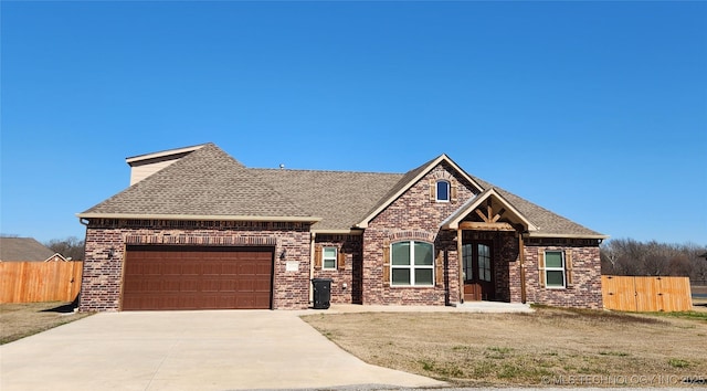 craftsman inspired home with fence, roof with shingles, concrete driveway, a garage, and brick siding