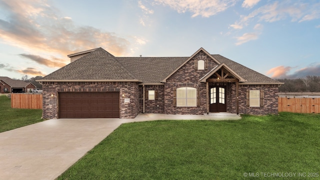 view of front of home with brick siding, fence, a front yard, a garage, and driveway