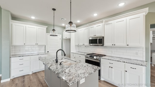 kitchen with visible vents, light wood-style flooring, white cabinets, stainless steel appliances, and a sink