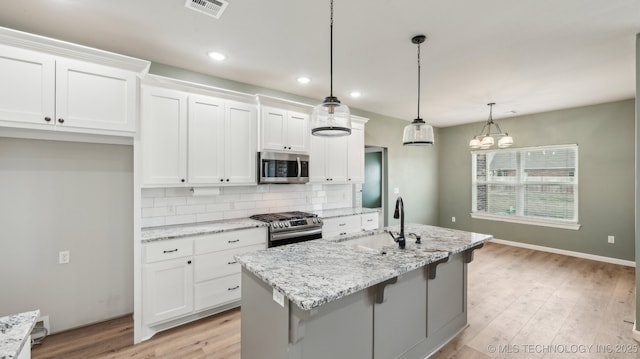 kitchen with a sink, white cabinets, visible vents, and stainless steel appliances