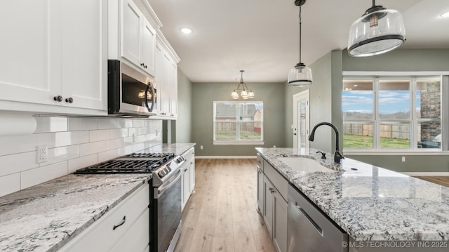 kitchen with a healthy amount of sunlight, a sink, stainless steel appliances, white cabinetry, and tasteful backsplash